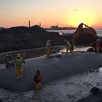 Llenado de una manguera SoilTain de Huesker con una excavadora para estructuras hidráulicas