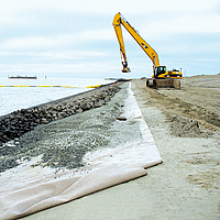 Trabajos de excavación en la playa para la colocación de piedras