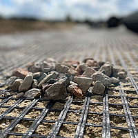 Detalle de la geomalla Basetrac Grid con pequeñas piedras sobre ella