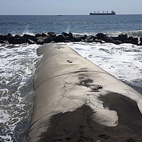 Escollera geotextil construida en el mar al fondo Bloques de agua contra los que chocan las olas