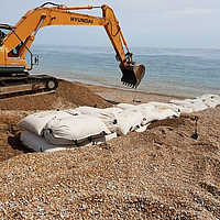 Instalación de bolsas SoilTain en una playa de grava con draga para protección contra inundaciones