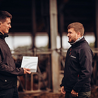 dos personas hablando mientras una sostiene un paquete Lubratec SmartBox