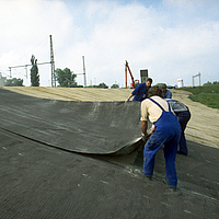 Trabajadores en el proceso de colocación de la estera de bentonita HUESKER en una obra de impermeabilización.
