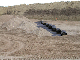 La grava se vuelca sobre geomallas Fortrac A enrolladas de aramida de alta resistencia, ideales para el refuerzo del suelo y la protección contra socavones.